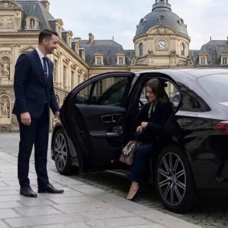 Chauffeur privé en costume ouvrant la portière d’une berline Mercedes noire à une cliente, devant l’hôtel de ville de Rennes